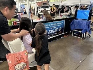 A father holds his daughter steady as she tackles her first virtual fish