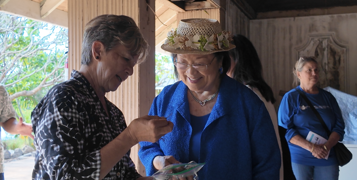 Mazie Hirono visiting with members of the Daughters of the American Revolution and local community members during an outdoor gathering at Kanewai Springs, engaged in discussion about the site and community matters.